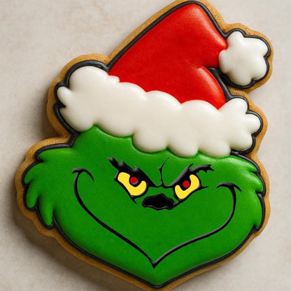 A festive cookie set inspired by The Grinch, including cookies shaped like the Grinch in a Santa hat, Max the dog with an antler, a Who girl with blonde braids and red bow, a crooked green Christmas tree with lights, and the Grinch’s green hand holding a red ornament.