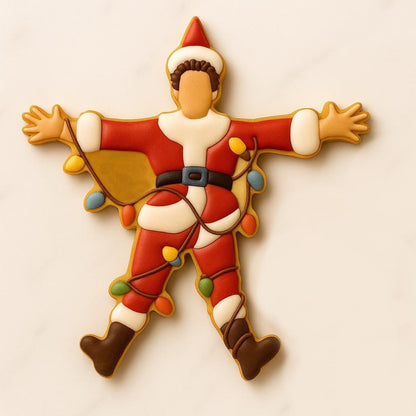 A set of decorated Christmas cookies inspired by the movie National Lampoon’s Christmas Vacation, including a car with a tree, moose mug, green trapper hat, Clark Griswold in a Santa suit tangled in lights, a roasted turkey, black cat with Christmas lights, “You Serious, Clark?” quote cookie, and an RV with a wreath.