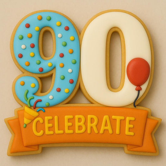 A sugar cookie shaped like the number 90, decorated with blue and cream icing. The number 9 is covered in rainbow sprinkles and a small confetti popper, the number 0 has a red balloon, and an orange banner below reads “CELEBRATE.”