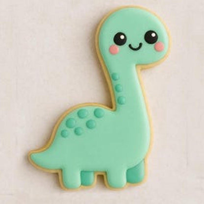 A sugar cookie shaped like a smiling mint-green dinosaur with a long neck, pink cheeks, and small raised green spots on its back, set against a light background.
