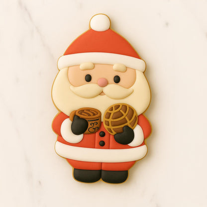 Decorated cookie shaped like Santa Claus holding a cup of café de olla and a traditional concha bread, on a light marble background.