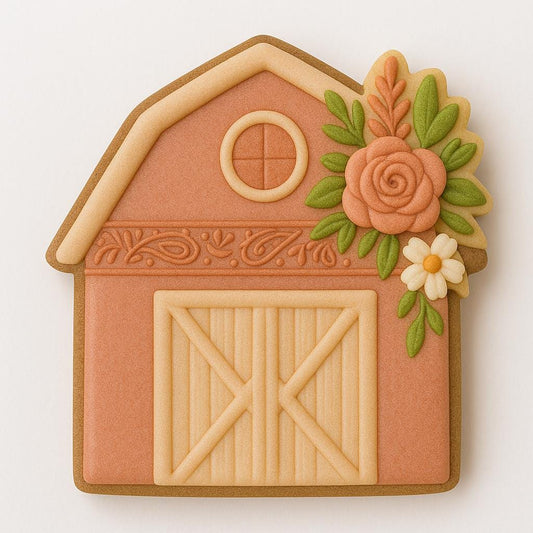 A barn-shaped cookie decorated in coral and cream tones, featuring barn doors, a small round window, and floral details with pink and white flowers and green leaves on the upper right side. The design blends rustic farmhouse charm with elegant boho style.