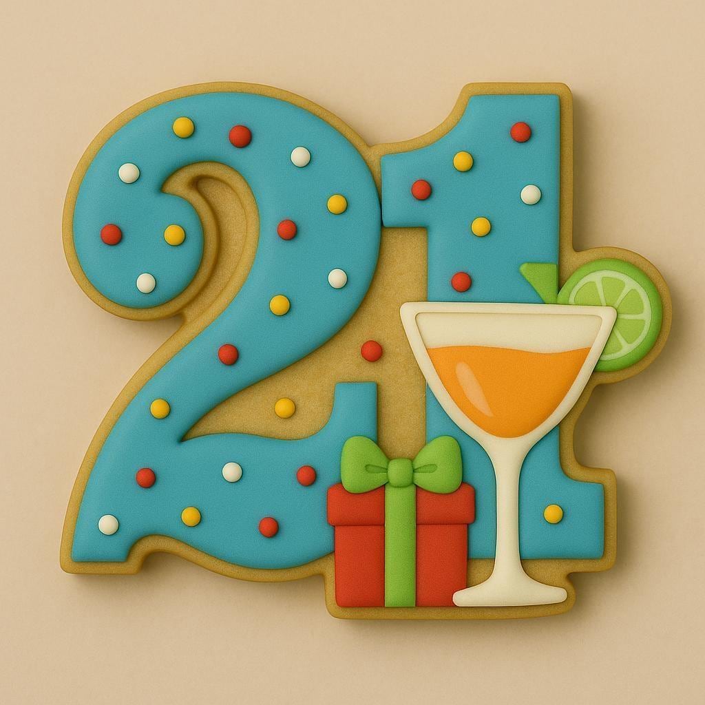 A sugar cookie shaped like the number 21, decorated with bright blue icing covered in colorful sprinkles, featuring a cocktail glass with an orange drink and lime garnish, and a red gift box with a green bow.