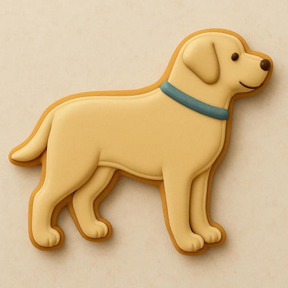 A sugar cookie shaped like a Labrador Retriever, decorated with yellow icing, a blue collar, and a happy expression on a beige background.