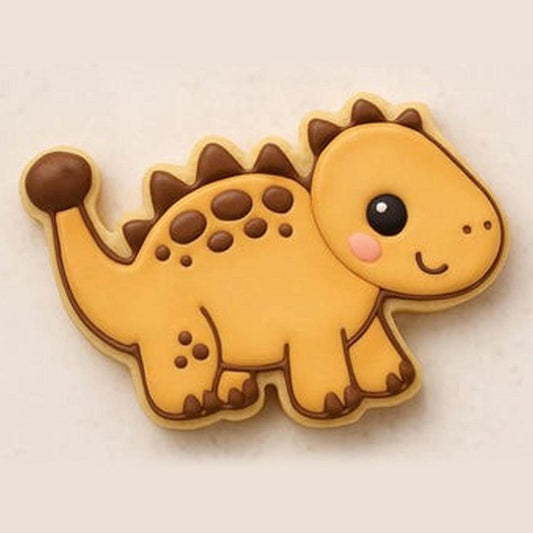A sugar cookie shaped like a smiling ankylosaurus dinosaur with yellow icing, brown spikes, and pink cheeks, placed on a light background.