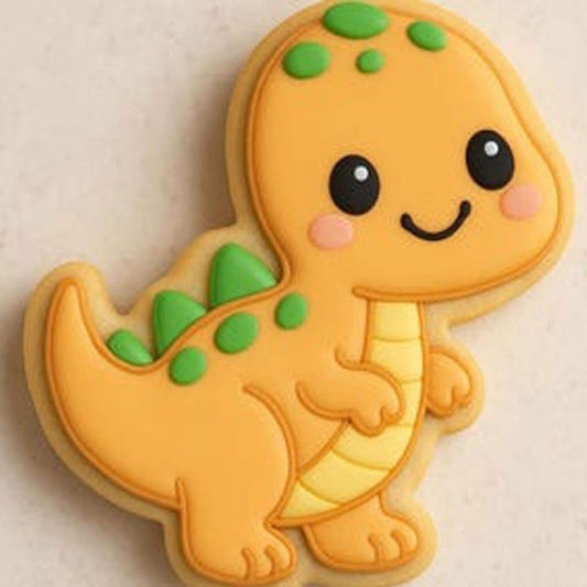 A sugar cookie shaped like a smiling orange dinosaur with green spikes and pink cheeks, decorated with yellow belly icing on a light background.