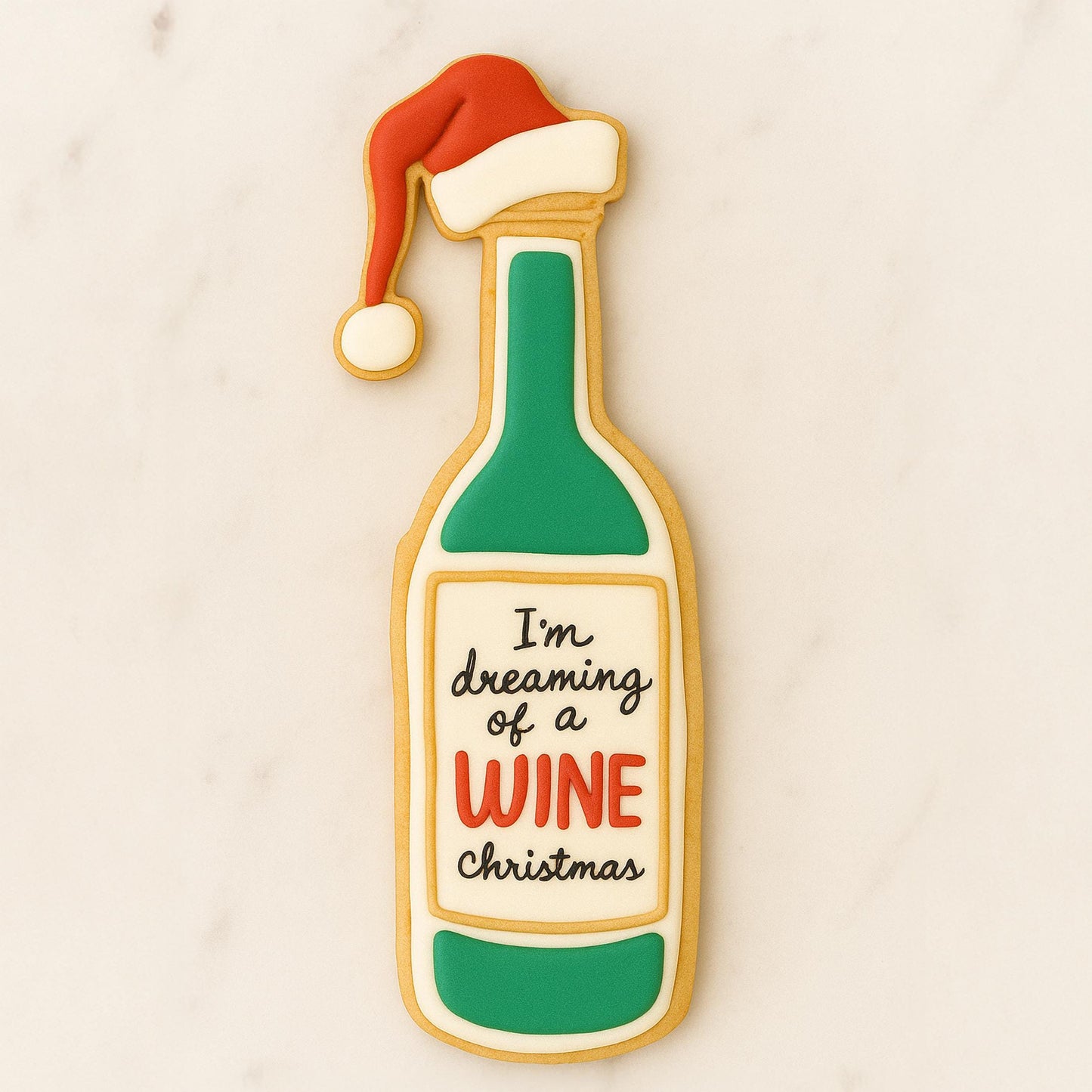 Decorated sugar cookie shaped like a wine bottle with a Santa hat and the phrase “I’m dreaming of a wine Christmas.”