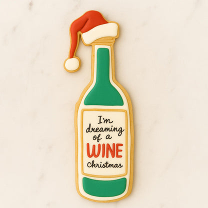 Decorated sugar cookie shaped like a wine bottle with a Santa hat and the phrase “I’m dreaming of a wine Christmas.”